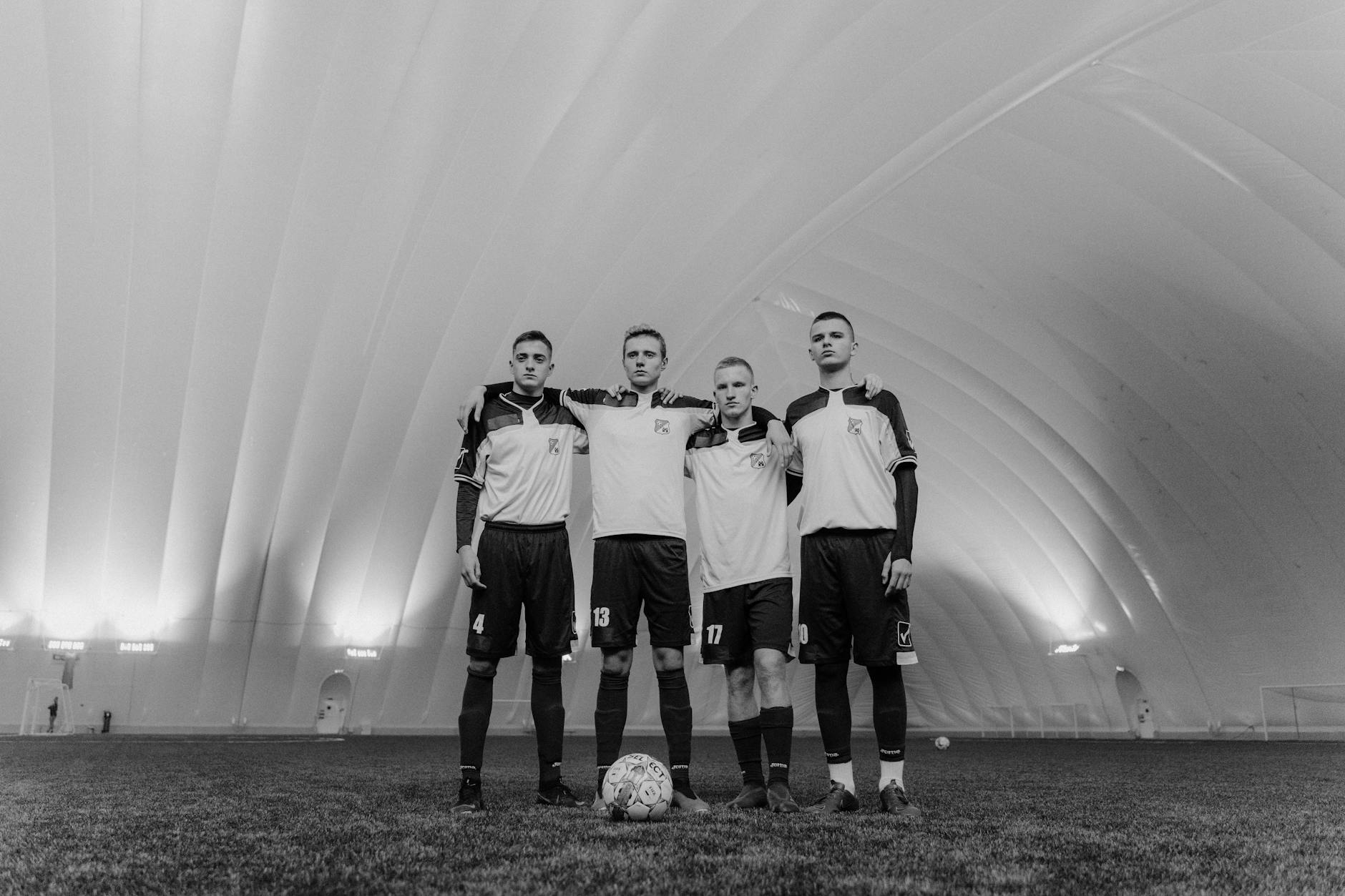 three men in white soccer jersey standing on green grass field